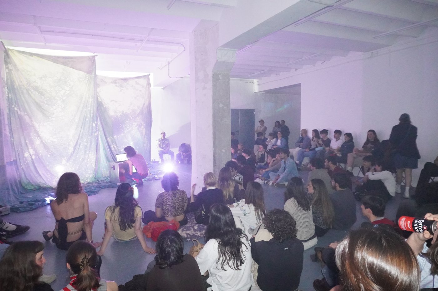 The audience sitting on the floor during a concert.