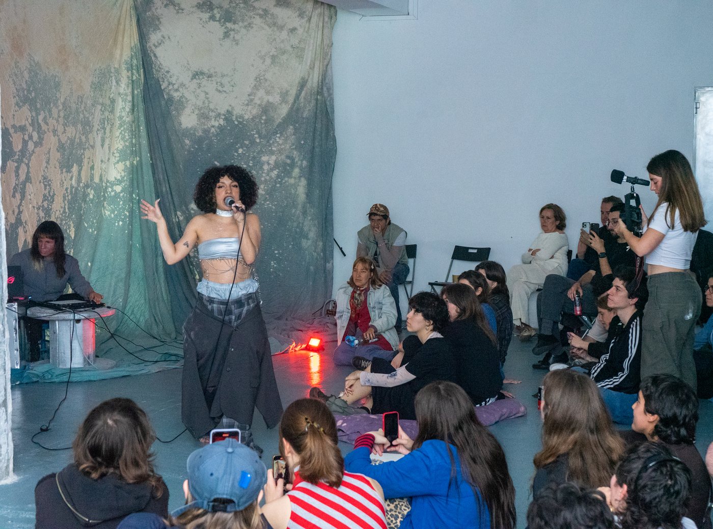 A singer performing among the audience sitting on the floor.