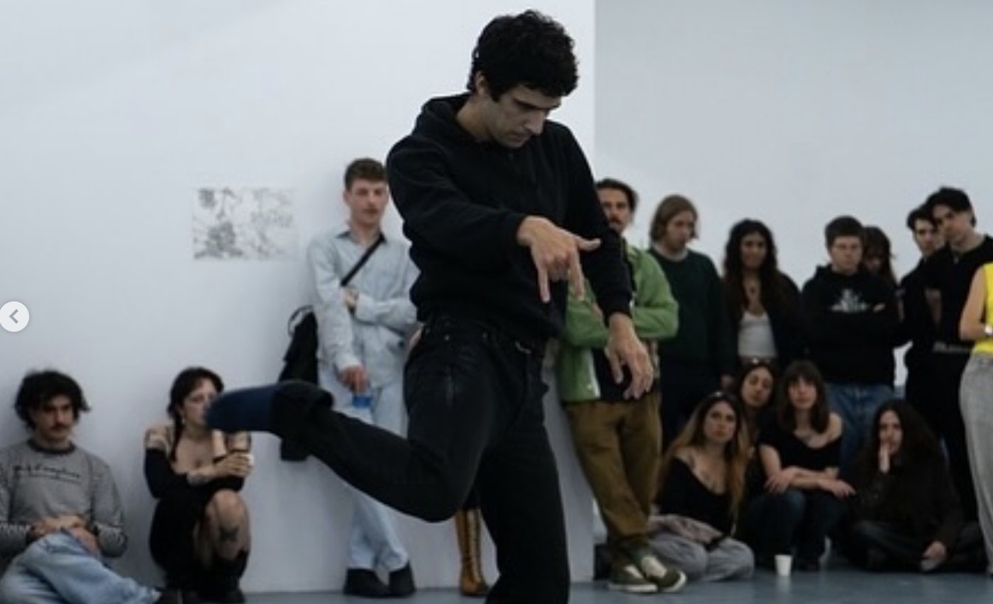 Guillem Jiménez of laSADCUM dancing in front of a crowd against a white wall.
