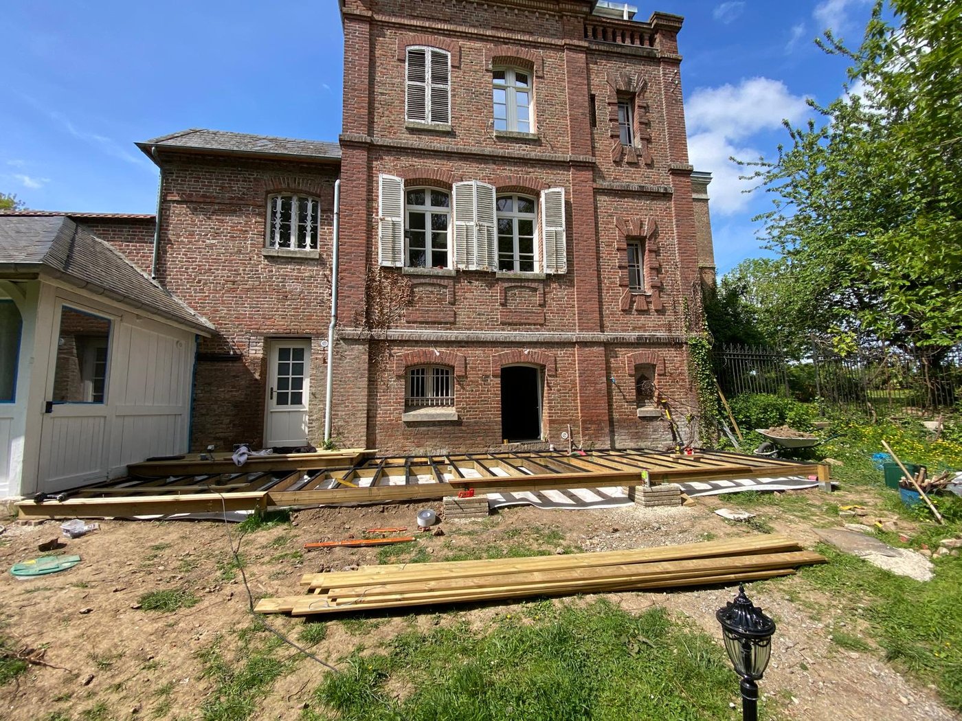 A wooden deck being built in front of a brick house, Château Le Bas Bleu.
